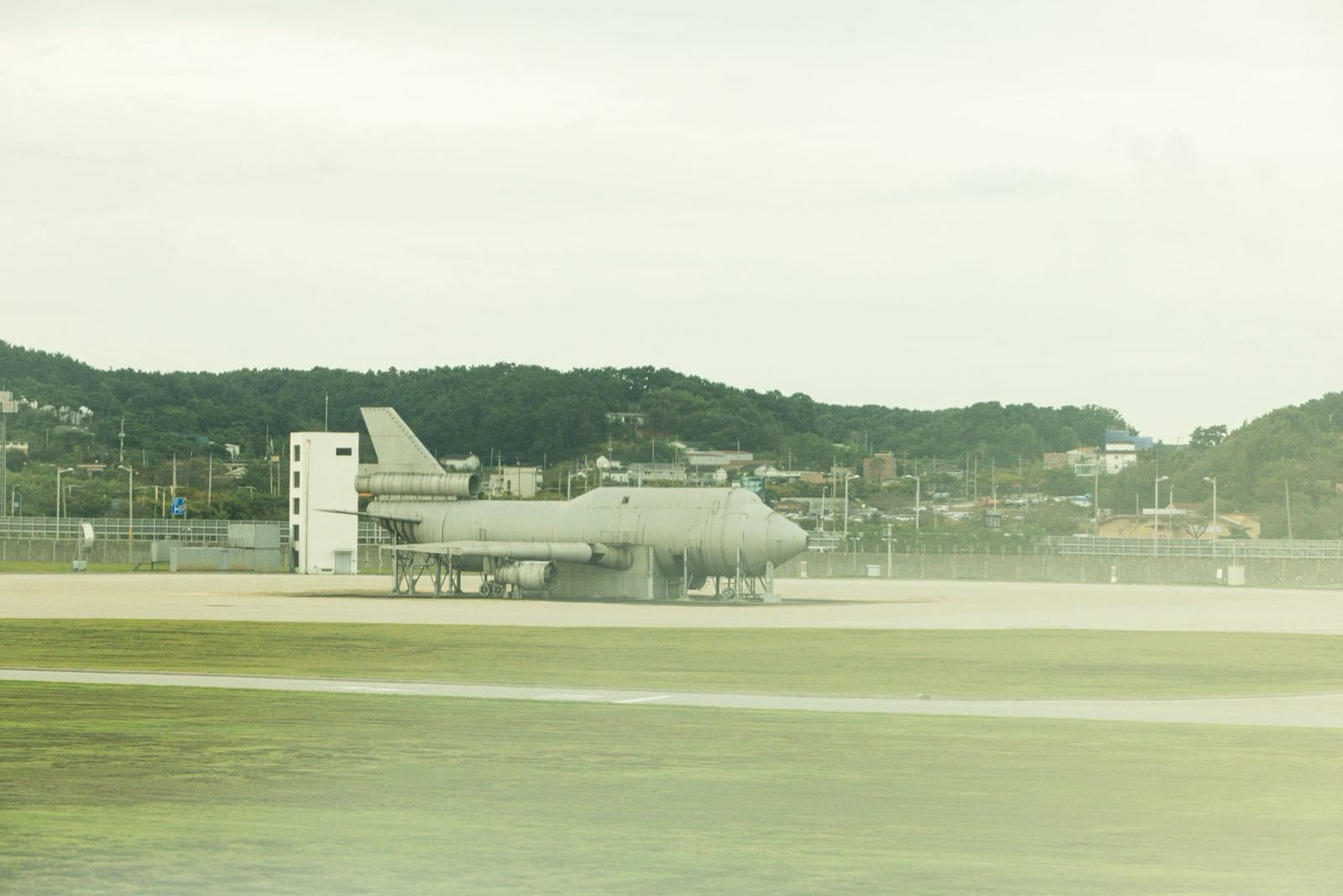 Un avión en la pista, visto desde lejos, en tono verde